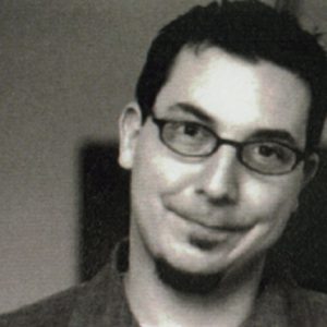 A black and white photo of a man wearing glasses.