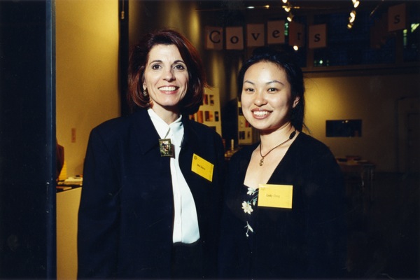A photo of two women dressed in suits and wearing yellow labels.
