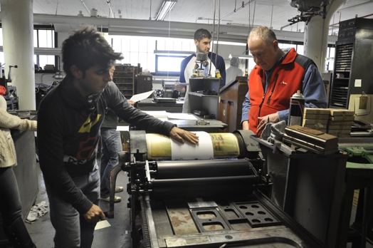 A photo of a group of people working at a printing press.