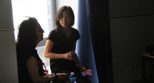 A photo of two women sitting next to a window in a room.