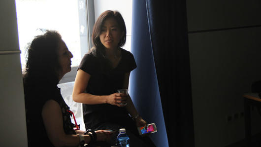 A photo of two women sitting next to a window in a room.