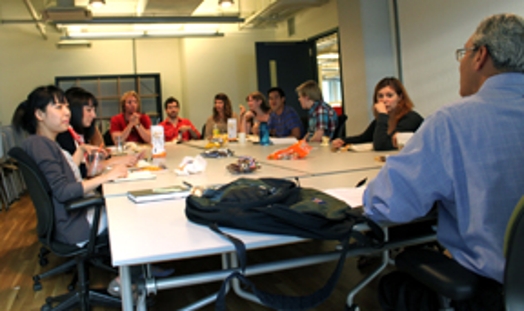 A photo of a group of people talking at a conference table.