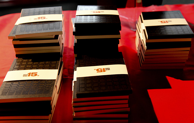 A photo of stacked books with a white band around each, that has a logo of MFA DESIGN 15.