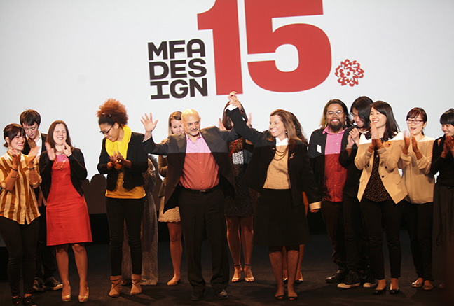 A photo of a group of people talking and applauding on a stage, while in the background is the text: MFA DESIGN 15.