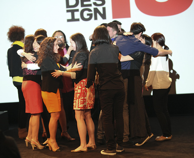 A photo of a group of people talking and hugging on a stage.
