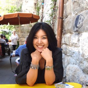 A photo of a woman sitting at a yellow table at a restaurant while in the background other peoples are served their beverages.