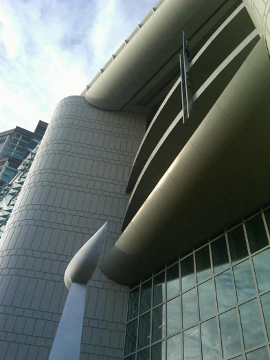 A photo of a modern, rounded building with glass architecture on its wall.