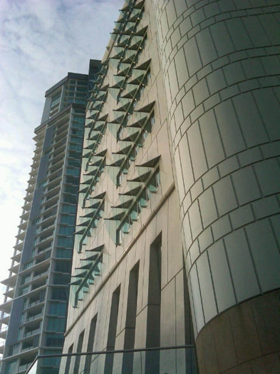 A photo of a modern building with glass architecture on its wall.