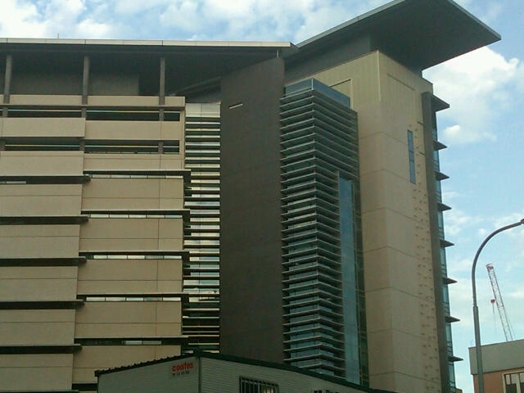 A photo of the side of a modern multistory brown building with balconies.