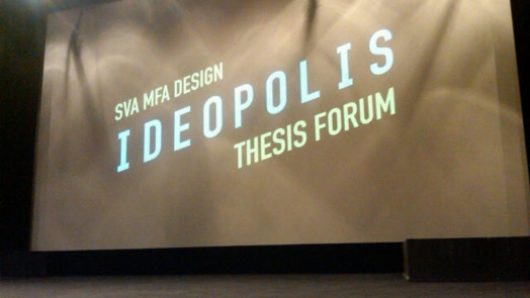 A photo of a stage and a projector screen with text: SVA MFA DESIGN IDEOPOLIS THESIS FORUM.