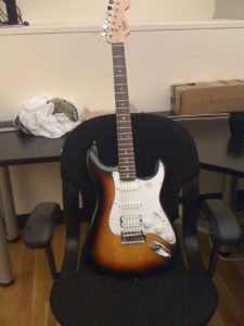 A photo of a rock guitar colored in brown and white that was put on a chair.