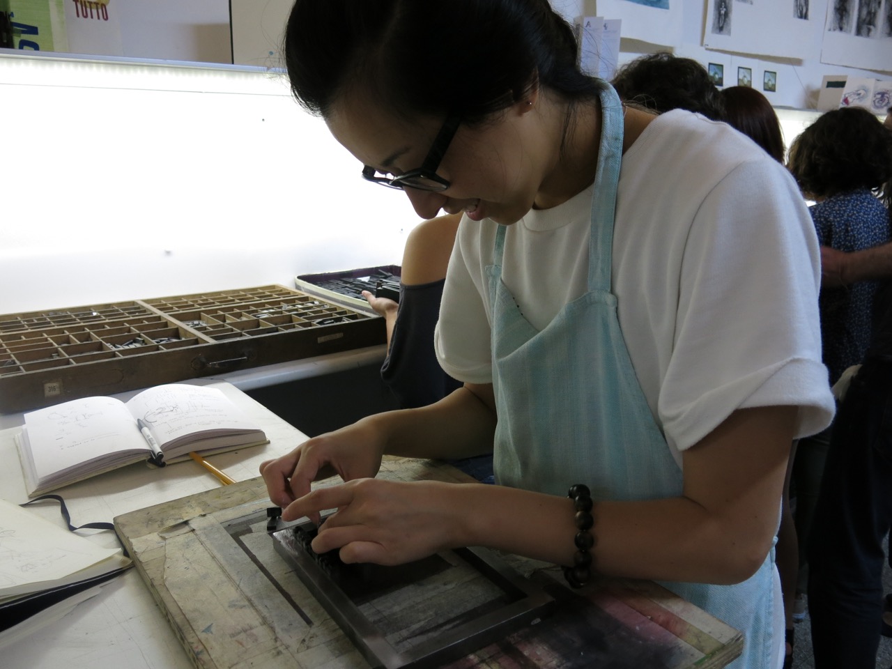 A photo of a woman working on some typography design in a workshop.