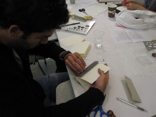 A photo of some students working with paper, trying to make a custom invitation card.