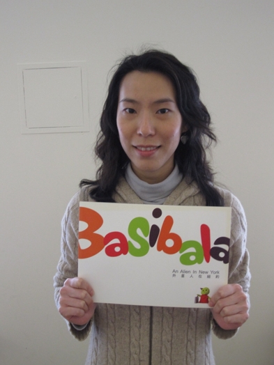 A photo of a women holding a banner with colorful letter text that says: Basibala.