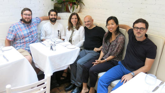 A photo of a group of people sitting around of a restaurant table.