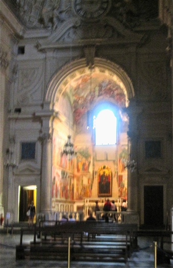A photo in a church of a stone arch with frescos.