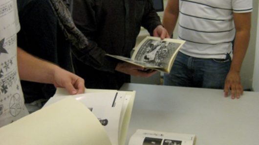 A photo of a group of people looking trough some artbooks.