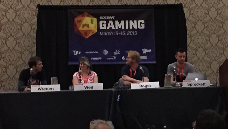 A photo of a group of people siting at a conference table in front of an advertisement regarding SXSW Gaming.