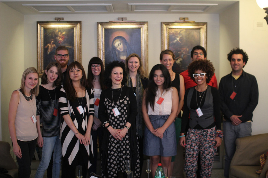 A photo of a group of students standing in front of three old paintings depicting Christian scenes.