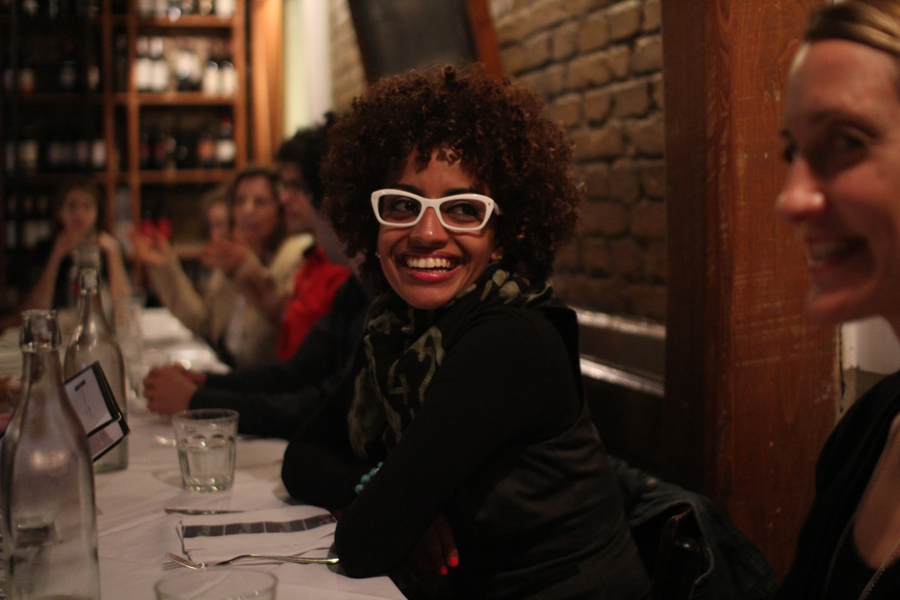 A photo of a woman wearing white glasses and sitting at a restaurant table.