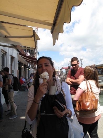 A photo of a girl enjoying an ice-cream while walking trough Venice.