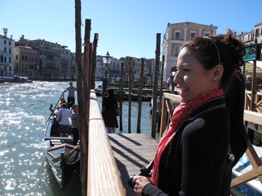 A photo of a woman siting on a boat wharf in Venice.