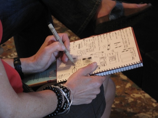 A photo of a person sketching some doodles in a notebook.