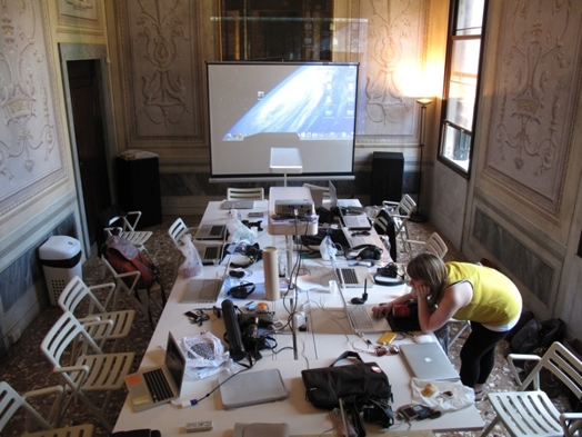 A photo of a presentation setup with laptops and a screen projector.