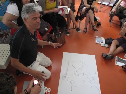 A photo of a person showing a drawing to a group of students.