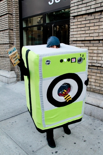 A person dressed as a green washing machine with a red and yellow sock sticking from it.