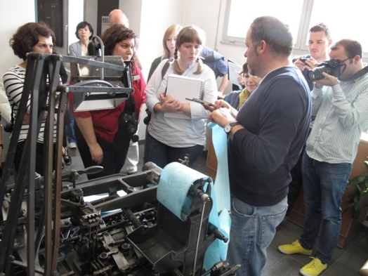 A photo of a group of people checking some blue paper material used in a printing press.
