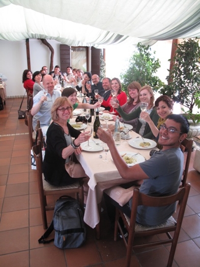 A photo of a group of people toasting a glass of champagne at a restaurant table.
