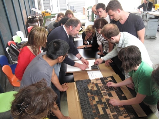 A photo of a group of people working with printing press metallic letters.