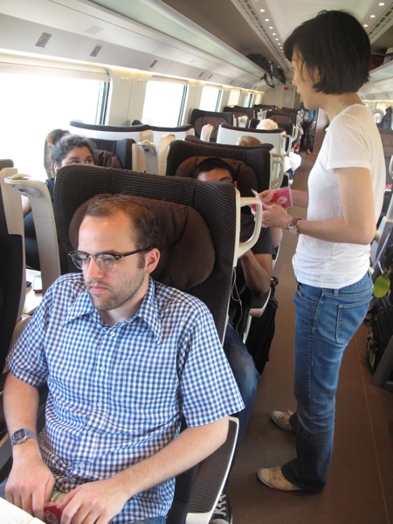 A photo of a group of people sitting in a bullet train and talking.