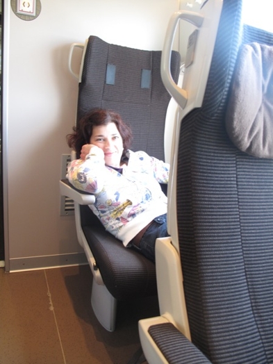 A photo of a woman leaning in a chair in a bullet train.