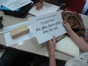 A photo of a piece of paper with typographic sample fonts that is held by a person.