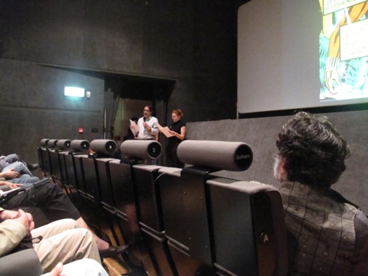 A photo of two people giving a lecture in a cinema.