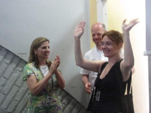 A photo of two people cheering a third one with her hands waving.