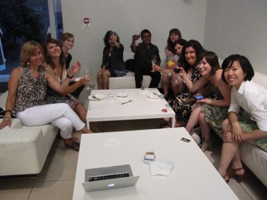A photo of a group of persons sitting on couches around the table and drinking from champagne glasses.