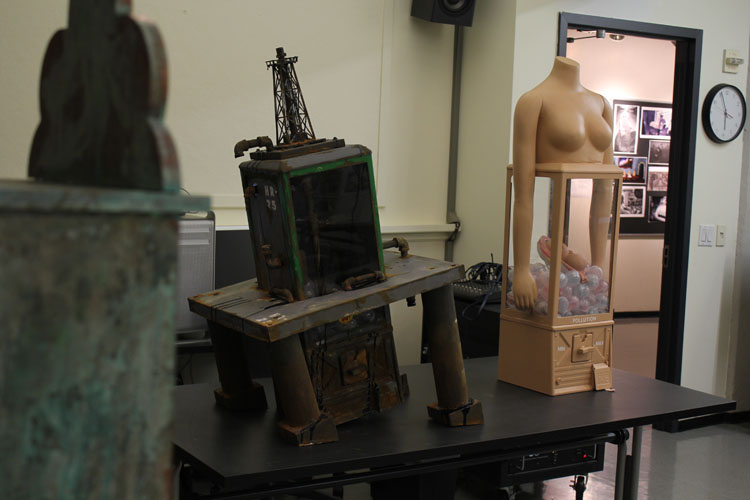 A photo from an art workshop showing a tilted oil derrick and a rubber ball vending machine that has on it the top half of a woman.
