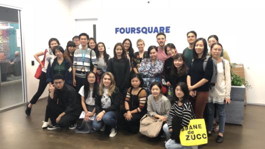 A group photo in an office and behind them, on a wall, the word Foursquare is visible.