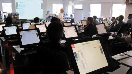 A photo of a classroom with computers and a screen projector.