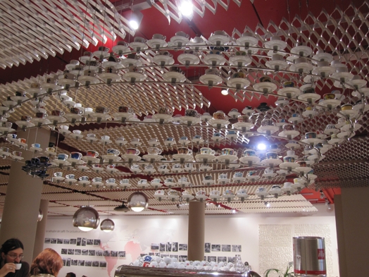 A photo of a round ceiling lamp made from coffee cups and plates.