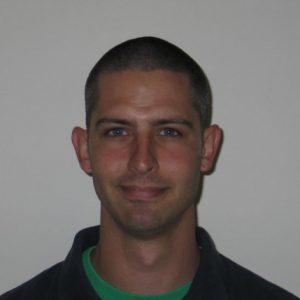A photo of a man wearing a green shirt and black blouse.