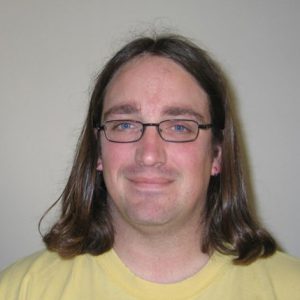 A photo of a man wearing glasses and a yellow shirt.