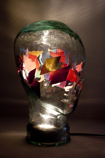 A human head made from glass filled with colored papers.