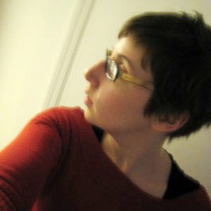A profile photo of a woman wearing glasses and a red shirt.
