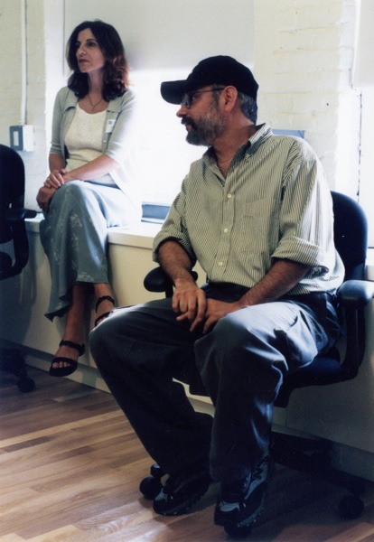 A photo of a man and a woman sitting in a room and looking at something.