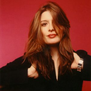 A photo of a woman in front of a red wall.