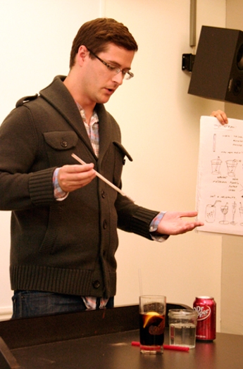 A man sampling some drinks from two glasses and a can with a straw.